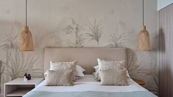 A bedroom with a large bed, two bedside tables, and two hanging lamps.