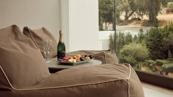 A modern living room with a sofa, a table with a bottle of champagne, glasses, and a fruit platter.