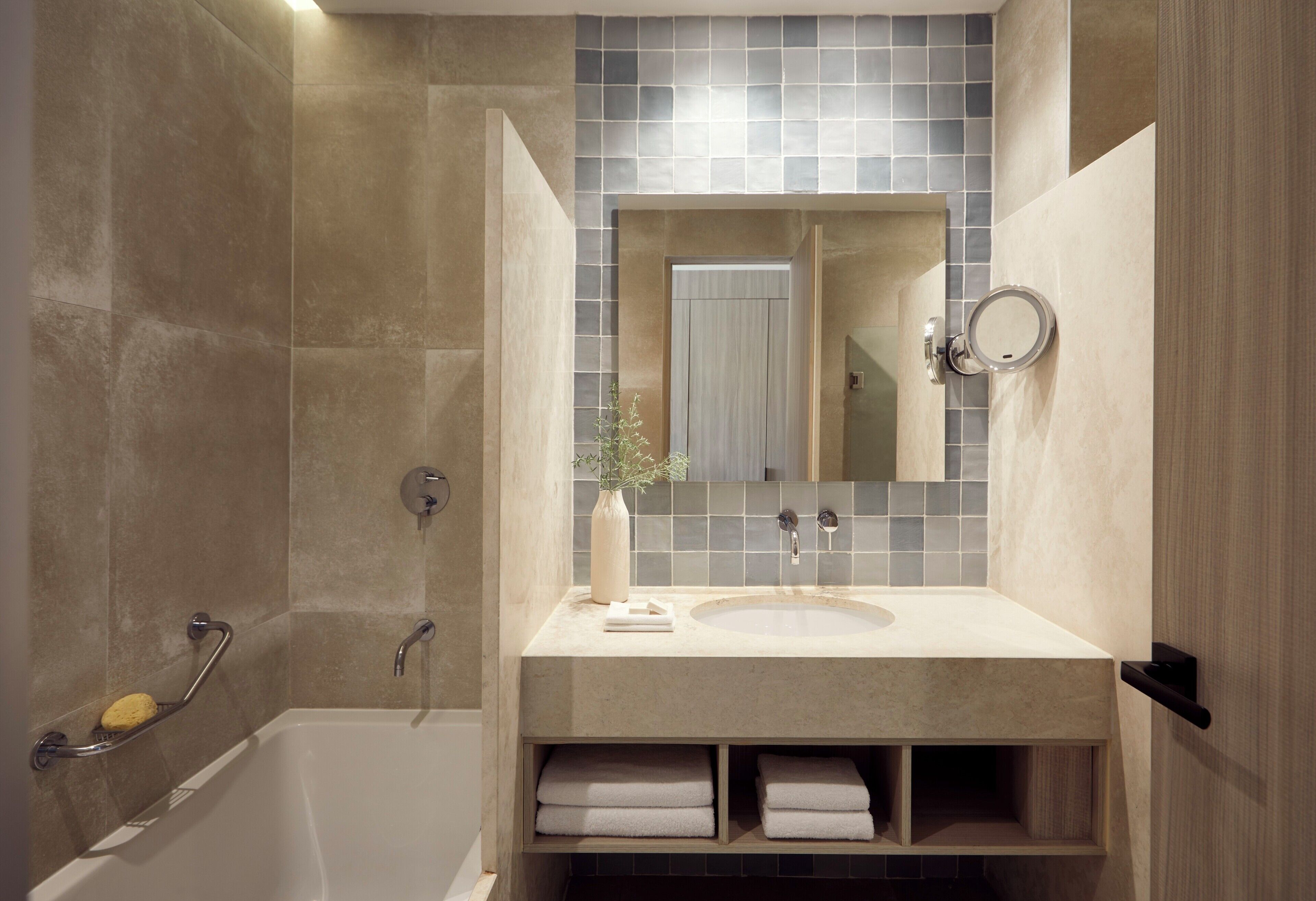 A bathroom with a bathtub, a sink, a mirror, and a towel rack.