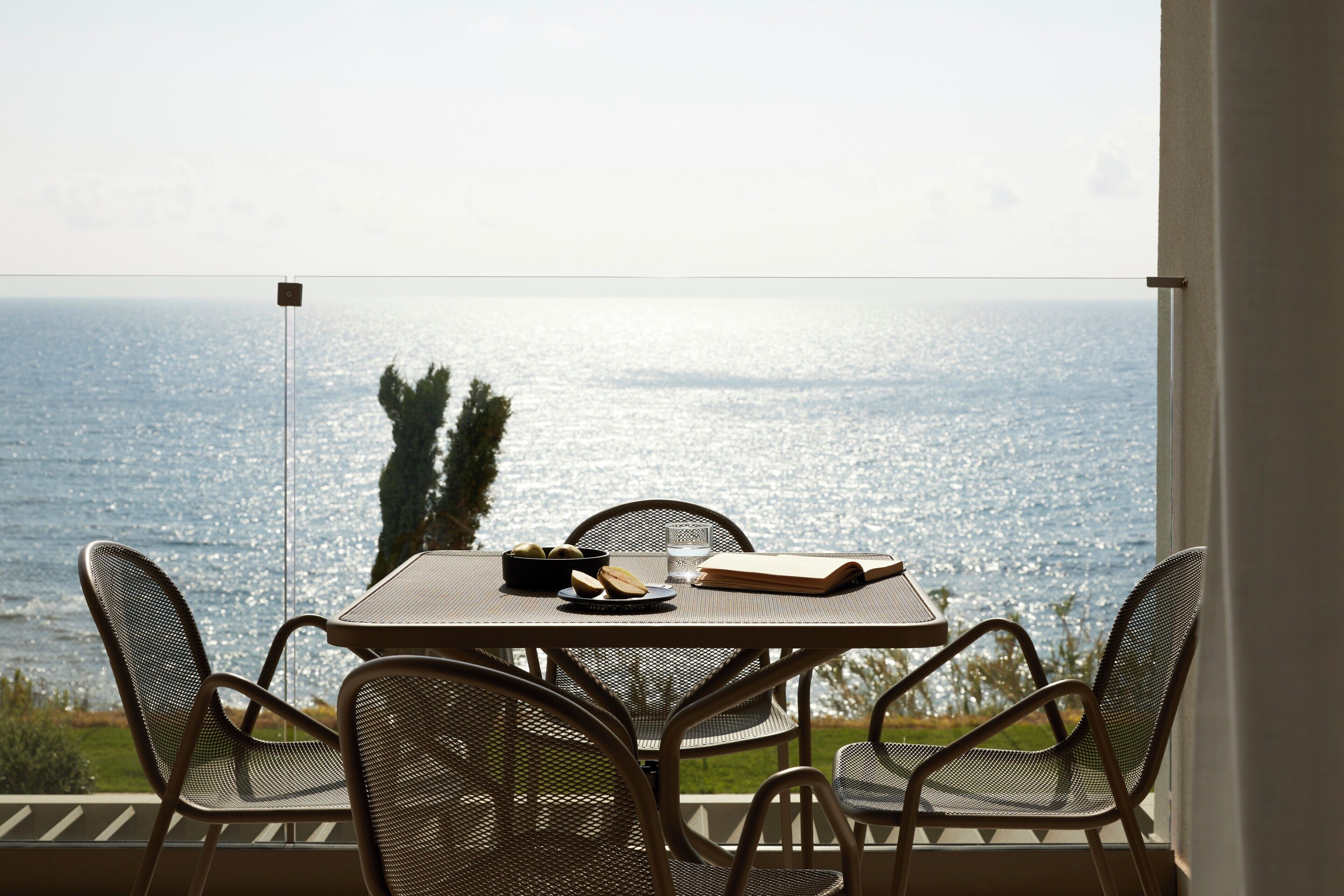 Uma mesa com cadeiras e vista para o mar.