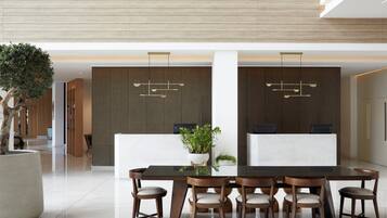 A modern reception desk with a minimalist design, a large potted plant, and a sleek dining area with a glass table and wooden chairs.