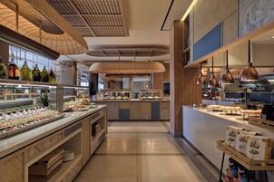 A modern kitchen with a central island, overhead lighting, and a variety of food items displayed.