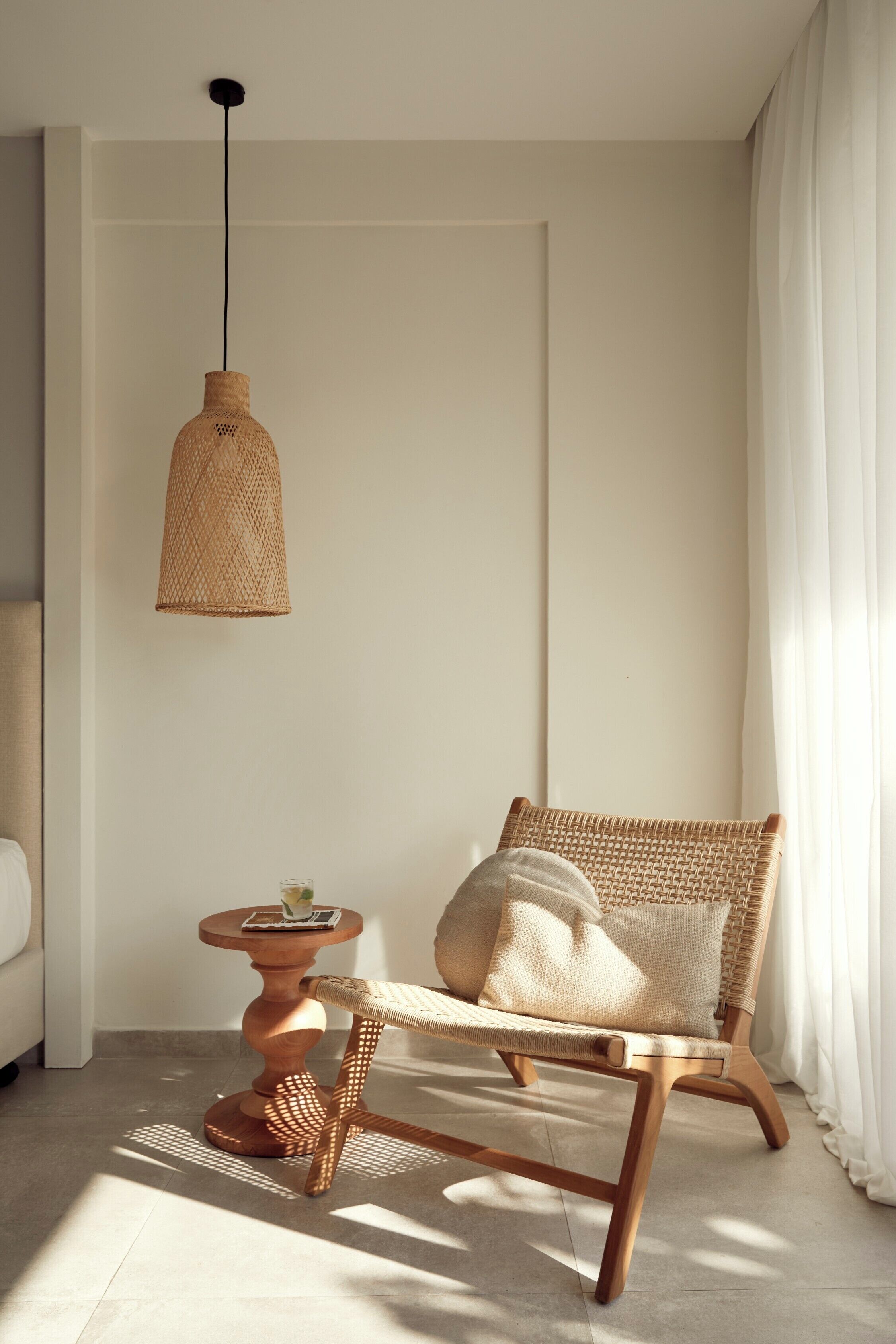 A room with a wicker chair, a small round table, and a hanging light fixture.