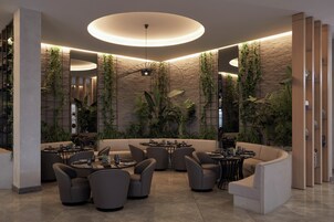 Un interior moderno con una zona de estar circular, un accesorio de iluminación central y vegetación vertical en las paredes.
