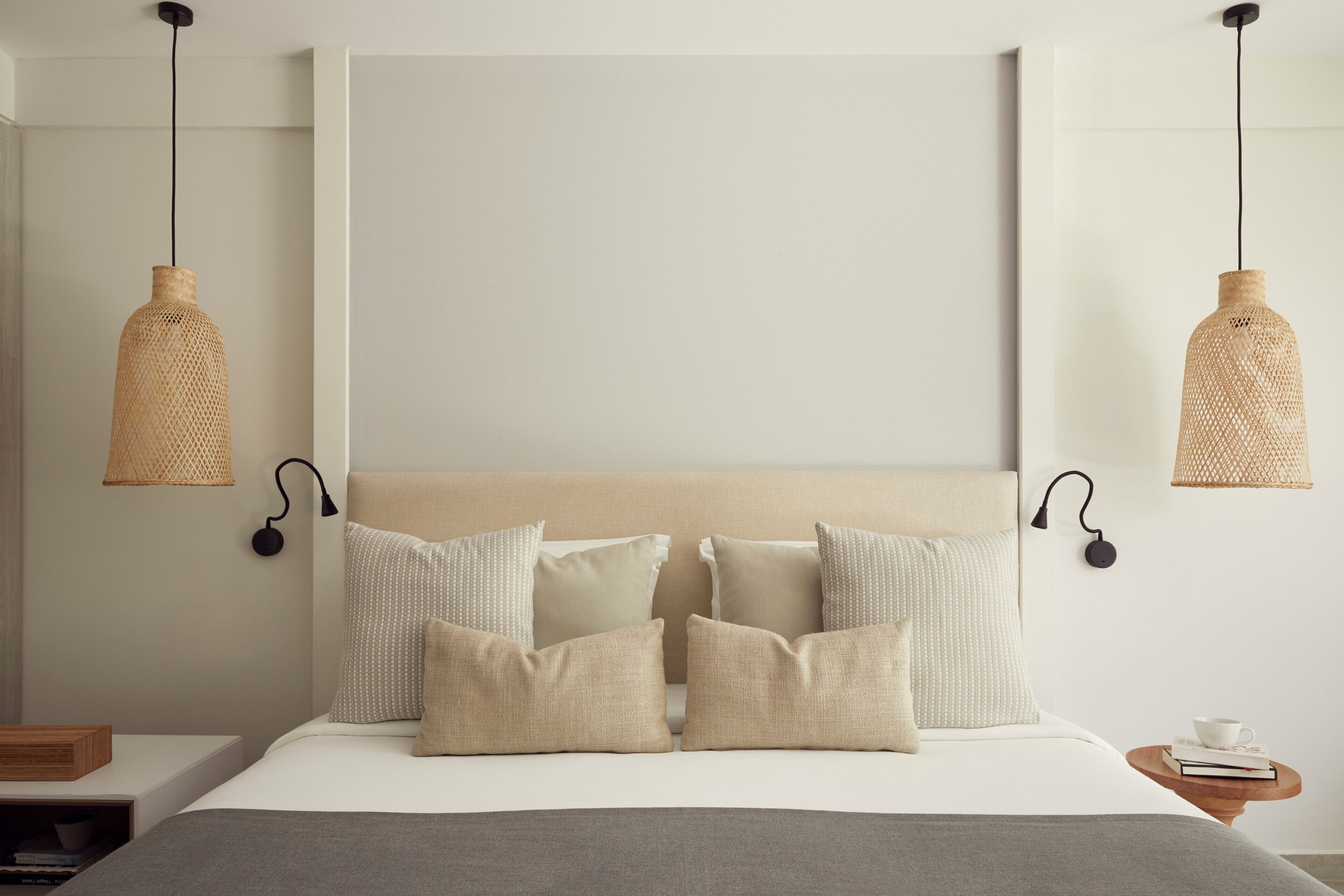 Ein Bett mit Kopfteil, mehreren Kissen und zwei Wandleuchten.