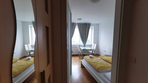 A modern hotel room with two single beds, a small dining table, and a chair. - Trnovo Apartment (Ljubljana)
