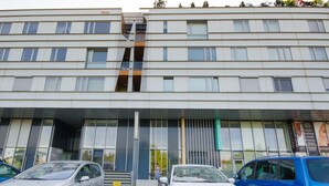 A modern building with a flat facade, multiple windows, and a central entrance with a glass door. - Trnovo Apartment (Ljubljana)