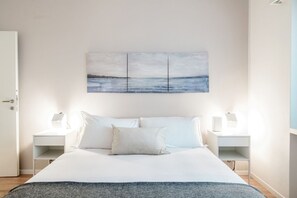 Un dormitorio con cama, dos mesitas de noche y un cuadro colgado en la pared.