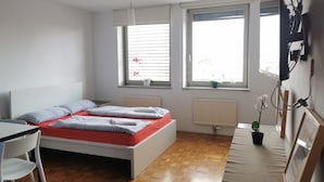 A modern bedroom with a bed, a desk, and two windows. - Dunajska Apartment (Ljubljana)
