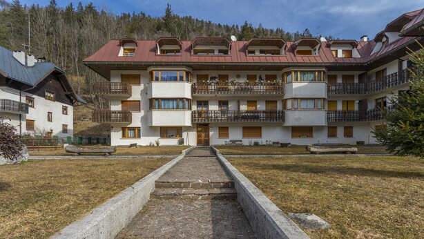 A multi-story hotel with balconies, a central courtyard, and a mountainous backdrop. - Modern APT in Tarvisio - 2 steps from the cycle route (Tarvisio)