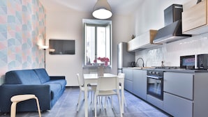 Une cuisine moderne avec un coin repas, un canapé et un téléviseur fixé au mur.