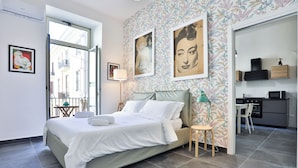 Une chambre moderne avec un grand lit, une petite table, une lampe et une vue sur l’extérieur.