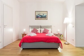 A bedroom with a bed, pillows, a bedside table, a lamp, and a framed picture on the wall. - OUI TREE Apartment (Naples)