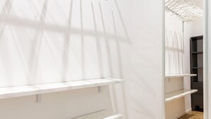 Un couloir avec des étagères blanches et un mur recouvert de miroirs.