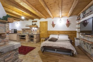 A rustic bedroom with a wooden ceiling, stone walls, a bed with a patterned duvet, and a stone fireplace. - Gorizia Sweet Minihouse with Parking (Gorizia)
