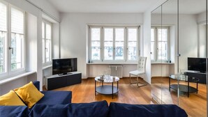 Un salon moderne avec un canapé, un téléviseur et une table basse en verre.
