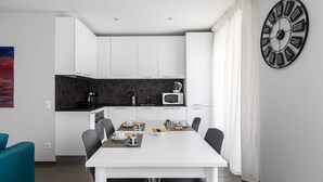 A modern kitchen with white cabinets, a black countertop, and a large wall clock.