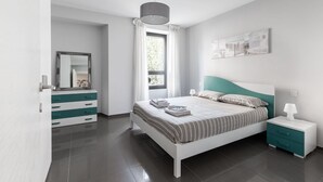 A modern bedroom with a bed, bedside table, and a dresser.