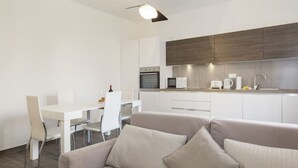 Eine moderne Küche mit weißen Schränken, einer Mikrowelle, einem Backofen und einem Spülbecken.