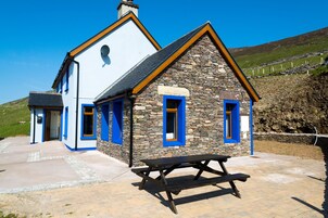 A two-story building with stone and white walls, blue-framed windows, and a picnic table in front.