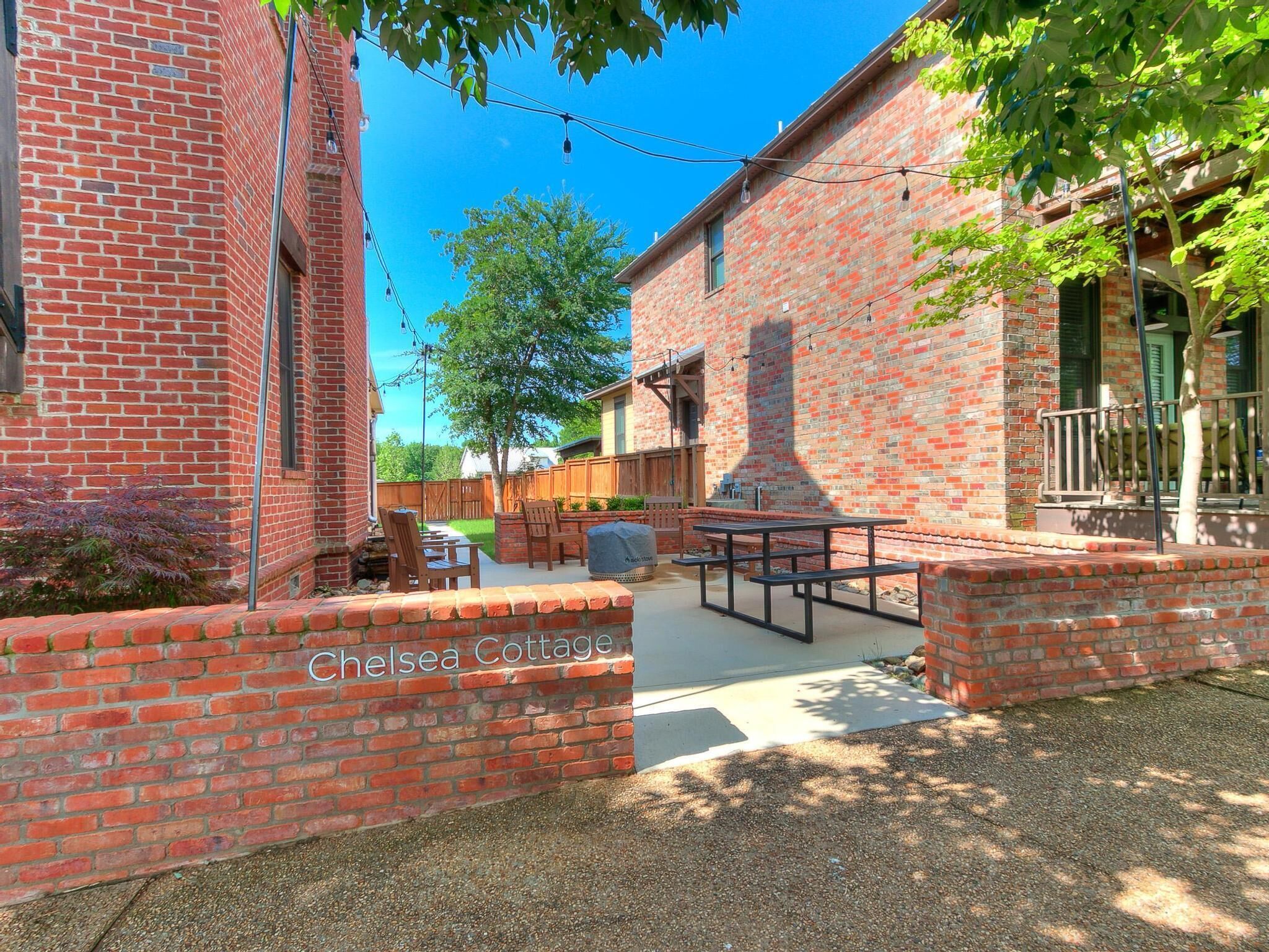 A brick building with a patio area, outdoor seating, and a sign reading "Chelsea Cottage".
