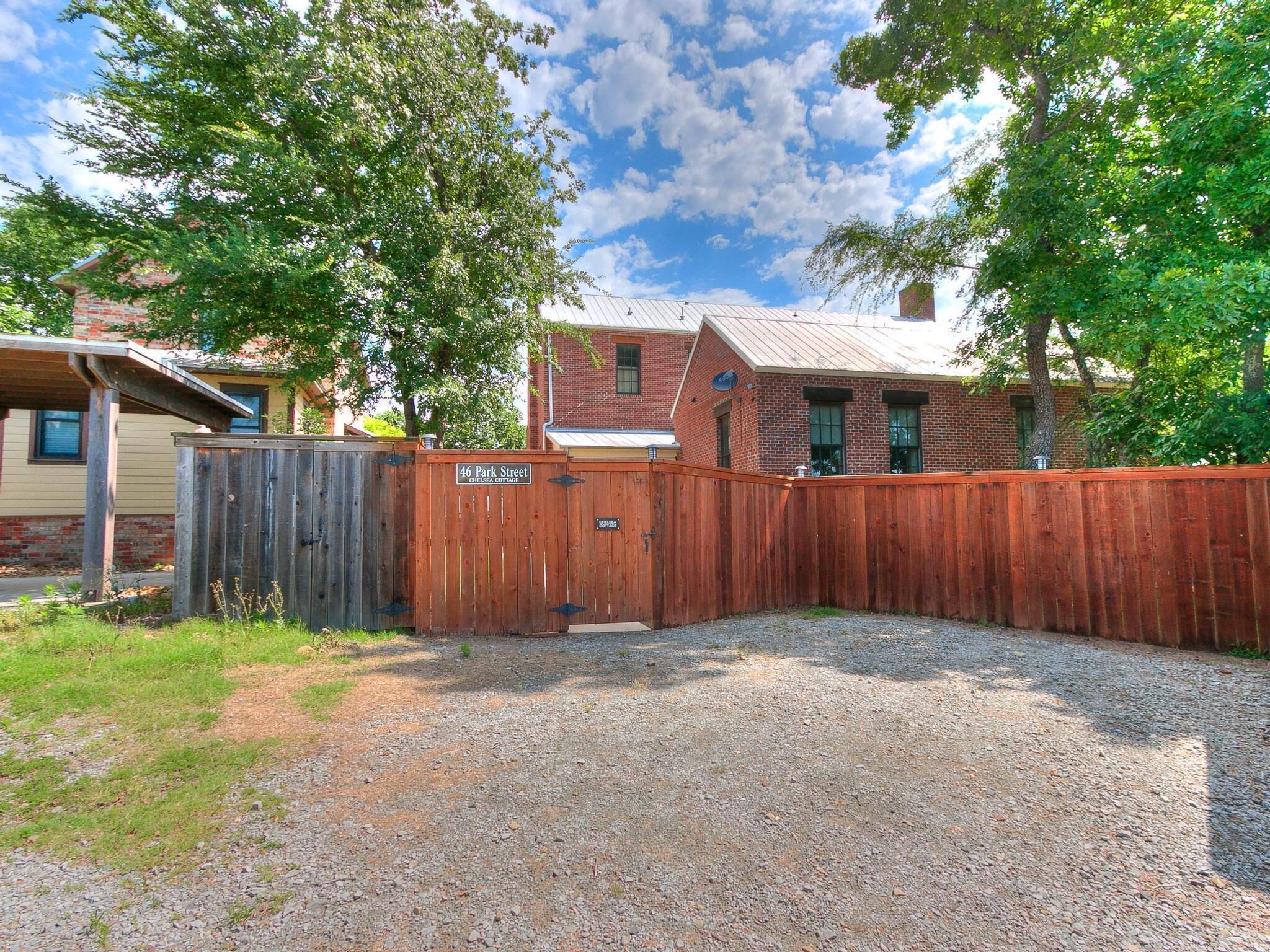 A fenced backyard with a gravel path leading to a wooden gate.