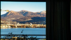Une vue d’une ville avec une montagne en arrière-plan, une étendue d’eau au premier plan et une grue visible sur la gauche.