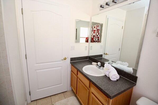 Un baño con una puerta blanca, un lavabo con un espejo encima y una toalla sobre la encimera.