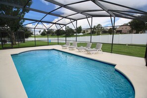 Una piscina techada con sillas de descanso y vista a un barrio residencial.
