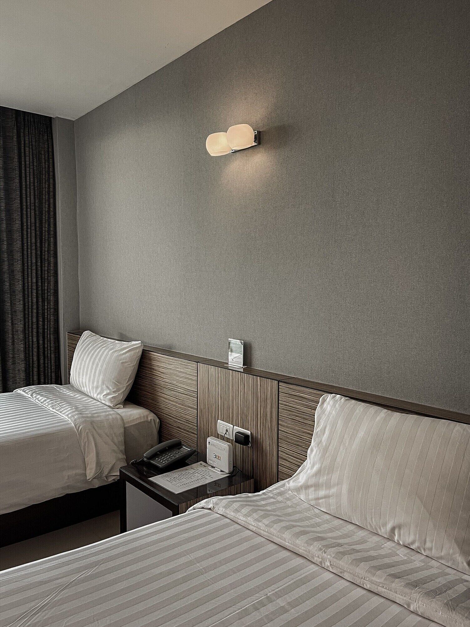 Ein Hotelzimmer mit zwei Betten, einem Nachttisch, einem Telefon und einer Wandleuchte.