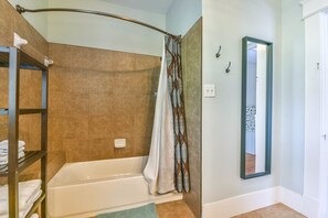 A bathroom with a bathtub, a shower curtain, a towel rack, and a mirror.