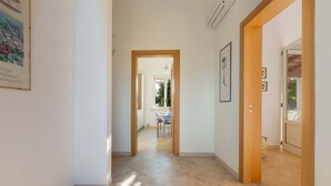 Un couloir avec un cadre de porte en bois, un sol carrelé et une vue sur un coin repas.