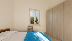 Une chambre à coucher avec un lit, une fenêtre, une chaise et une armoire.
