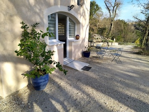 A building with a white exterior, a small porch, a potted plant, and a table with chairs outside.
