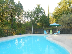 A swimming pool with two lounge chairs and a green umbrella.