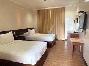 A hotel room with two beds, a desk, a television, and a window with curtains. - Dotties Place Hotel and Restaurant (Butuan)