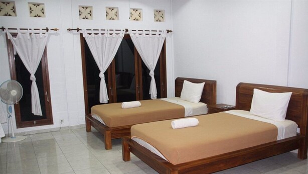 A room with two wooden beds, white curtains, a standing fan, and a tiled floor. - Dono Guest House (Ubud)