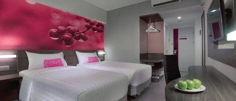 A modern hotel room with two beds, a dining table with apples, a TV, and a wall with a red floral design.