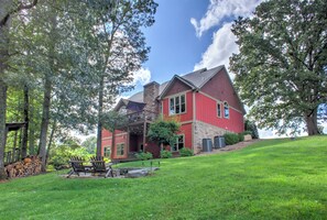 Una casa roja con una chimenea de piedra, un porche y un césped bien cuidado.