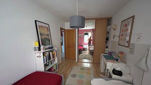 Ein Zimmer mit einem Bett, einem Schreibtisch, einem Bücherregal und einer Tür zu einem weiteren Raum.