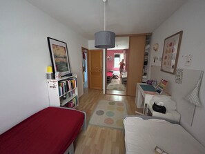 A room with a bed, a desk, a bookshelf, and a door leading to another room. - Pleasant air-conditioned family home with swimming pool and garden (Caumont-sur-Durance)