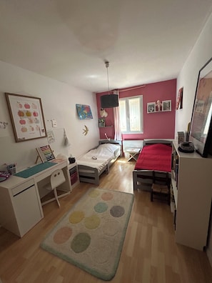 Un dormitorio con cama, escritorio, silla y una ventana pequeña.