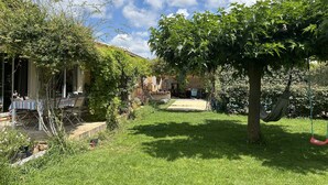 Ein Garten mit Essbereich, einer Hängematte und einem Baum.