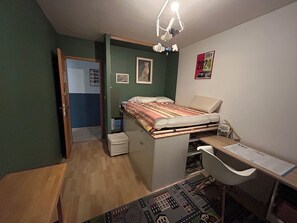 A compact bedroom with a bed, desk, and chair, a small window, and a door leading to another room. - Cozy, air-conditioned family home with a pool and garden (Caumont-sur-Durance)