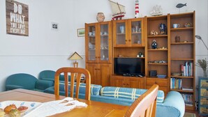 Uma sala de estar com um armário de madeira, uma televisão e uma estante.