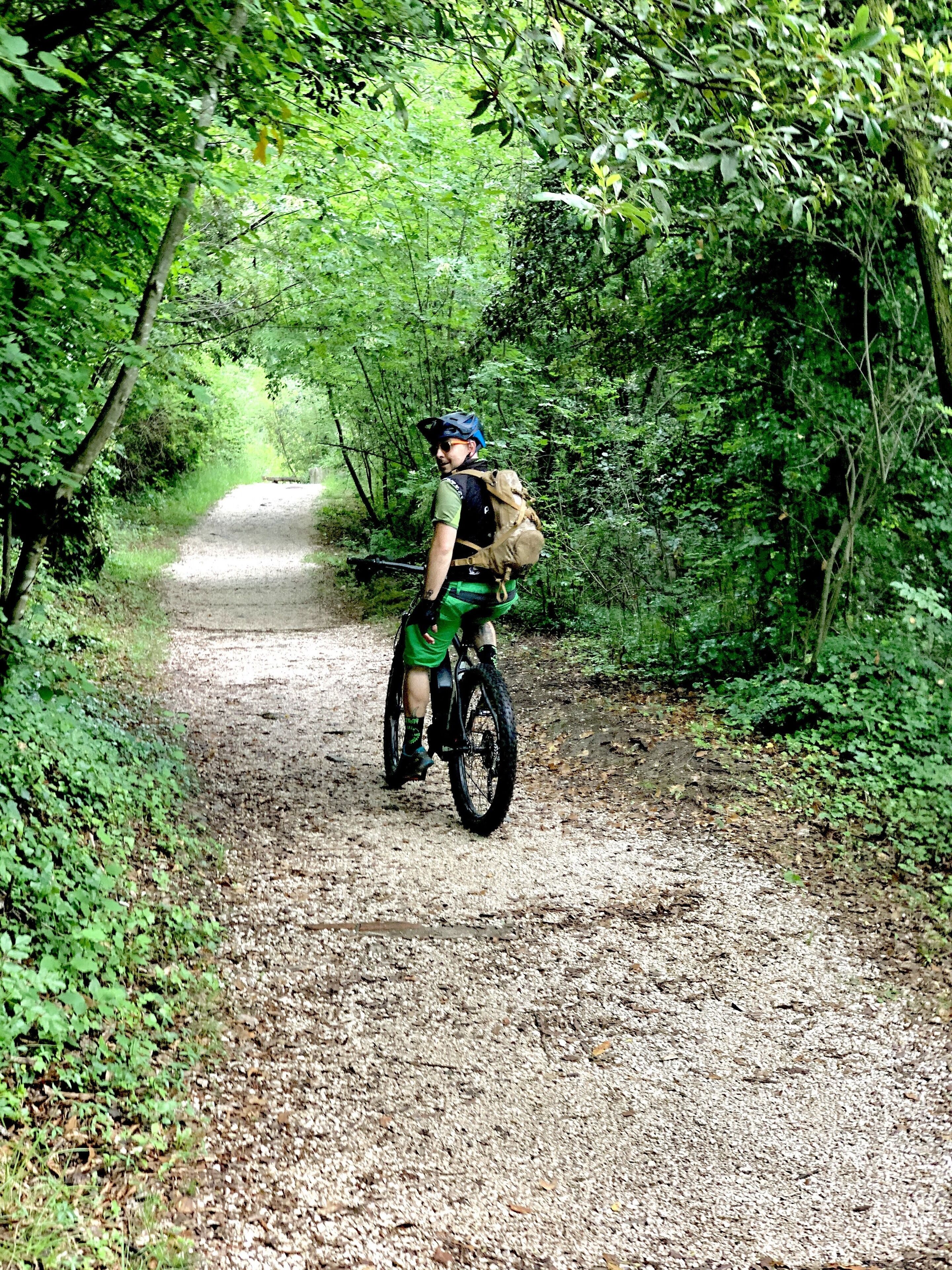En person cykler på en grusvej omgivet af frodig vegetation.
