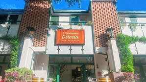 A building with a sign reading "L'Ennesima Osteria Con Alloggi".