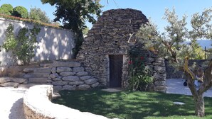A stone structure with a door, surrounded by grass and trees. - Pretty stone house with swimming pool near Gordes (Gordes)