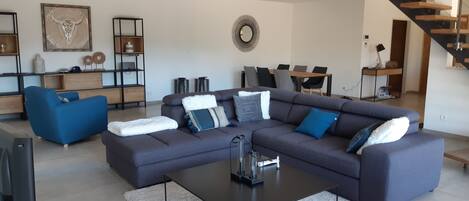 A modern living room with a sectional sofa, a coffee table, and a dining area with a table and chairs.
