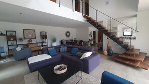 A spacious living area with a large sectional sofa, a coffee table, and a staircase leading to an upper level. - Pretty stone house with swimming pool near Gordes (Gordes)